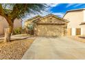 Tan house with a two-car garage and landscaping at 15348 W Banff Ln, Surprise, AZ 85379