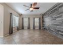 Spacious living room with tile floors, three windows, and a wood-look accent wall at 3647 W Thalia Ct, Phoenix, AZ 85086