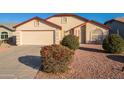 Tan house with red roof and a two-car garage.Landscaped front yard at 4872 E Sandwick Dr, San Tan Valley, AZ 85140