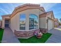 Close-up of stucco home with manicured lawn, stone accents and an attached two-car garage at 1041 N 91St Pl, Mesa, AZ 85207