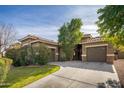 Tan two-story house with a three-car garage and lush landscaping at 1523 E Constance Way, Phoenix, AZ 85042