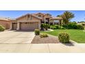 Tan two-story house with a lush green lawn and mature shrubs at 302 S Laguna Dr, Gilbert, AZ 85233