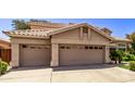 Two-story house with tan exterior, double garage doors, and nicely landscaped yard at 302 S Laguna Dr, Gilbert, AZ 85233