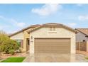 Tan house with a brown garage door and small front yard at 5590 W Victory Way, Florence, AZ 85132