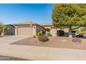 Single-story home with tan exterior, two-car garage, and mature landscaping at 26458 W Yukon Dr, Buckeye, AZ 85396