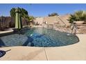 Sparkling pool with an umbrella, decorative waterfall, and landscaped surroundings for outdoor enjoyment at 3560 W Tina Ln, Glendale, AZ 85310