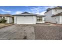 Front view of a single-story house with a white garage door and rock landscaping at 8728 W Vale Dr, Phoenix, AZ 85037