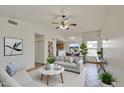 Bright living room with ceiling fan, open floor plan, stylish furniture, and view into kitchen/dining areas at 8728 W Vale Dr, Phoenix, AZ 85037