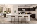 Modern kitchen with dark cabinetry, marble countertops, and breakfast bar at 1820 N 94Th Gln, Phoenix, AZ 85037