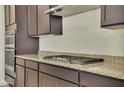 Gas cooktop with dark brown cabinetry and granite countertops at 19587 W Marshall Ave, Litchfield Park, AZ 85340