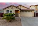 Tan house with a two-car garage and desert landscaping at 24246 W Tonto St, Buckeye, AZ 85326