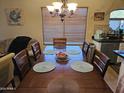 A wood dining table features seating for six under a chandelier and natural lighting at 43726 W Carey Dr, Maricopa, AZ 85138