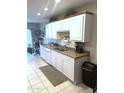 View of the well-lit kitchen featuring white cabinets, tile floors, and stainless steel sink at 455 S Delaware Dr # 117, Apache Junction, AZ 85120