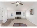 Spacious living room featuring neutral carpet, ceiling fan, and entertainment center at 44520 W Windrose Dr, Maricopa, AZ 85138
