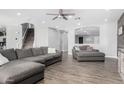 Open living area with L-shaped sofa, wood floors, and a view of the staircase at 12113 W Planada Ln, Sun City, AZ 85373