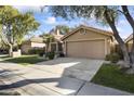 Tan house with attached garage, landscaping, and a paved driveway at 15801 N 51St St, Scottsdale, AZ 85254