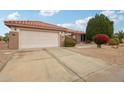 Tan house with a two-car garage and nicely landscaped yard at 16220 W Red Rock Dr, Surprise, AZ 85374