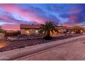 Charming ranch house exterior at sunset, with a palm tree and stone landscaping at 18509 W Bethany Home Rd, Litchfield Park, AZ 85340