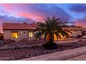 Lovely ranch house exterior at sunset, with a palm tree and stone landscaping at 18509 W Bethany Home Rd, Litchfield Park, AZ 85340