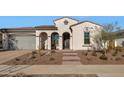 Front view of a single-story house with a gray garage door and arched entry at 5252 N 206Th Dr, Buckeye, AZ 85396