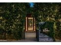 Exterior entrance featuring lush greenery, a decorative metal door, and warm lighting at 6529 E Camino De Los Ranchos St, Scottsdale, AZ 85254