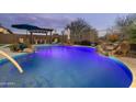 Luxury pool with waterfall feature and colorful lighting at 11971 E Chevelon Trl, Gold Canyon, AZ 85118