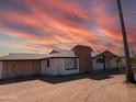 White, ranch-style house needing some repairs, set against a dramatic sunset at 33767 W Grande Rd, Stanfield, AZ 85172