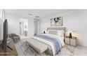 A bright bedroom featuring a large bed, a sitting area, and a view into the bathroom at 5857 S Romano --, Mesa, AZ 85212