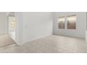 A living room with neutral tile floors, white walls, and two bright windows at 7694 W Crabapple Dr, Peoria, AZ 85383