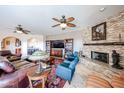 Cozy living room with a stone fireplace, ceiling fans, comfortable seating, and tile flooring at 9015 E Hackamore Dr, Scottsdale, AZ 85255