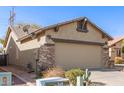 Rear view of tan house with stone accents and two-car garage at 11153 E New Frontier Ct, Gold Canyon, AZ 85118