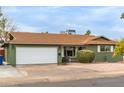 Green single story home with a two car garage and well manicured landscaping at 2053 E Minton Dr, Tempe, AZ 85282