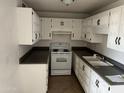 White kitchen cabinets, dark countertops, and electric range at 3120 N 67Th Ln # 42, Phoenix, AZ 85033
