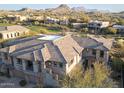 Gorgeous aerial view of a multi-story home showcasing tile roof, stone accents, desert landscaping, and a mountain backdrop at 10260 E White Feather Ln # 1038, Scottsdale, AZ 85262