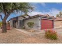 Single story home with gray exterior, red garage door and nicely landscaped yard at 14805 W Caribbean Ln, Surprise, AZ 85379