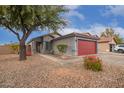 One-story home with gray exterior, red garage door, and desert landscaping at 14805 W Caribbean Ln, Surprise, AZ 85379