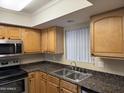 Kitchen features wood cabinets, granite countertops, and a double sink at 3405 W Danbury Dr # D121, Phoenix, AZ 85053