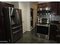 Bright kitchen featuring stainless steel appliances, dark wood cabinets, and stylish backsplash at 50530 W Mockingbird Ln, Maricopa, AZ 85139