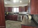 Kitchen featuring stainless appliances, dark countertops, and dark wood cabinets at 50530 W Mockingbird Ln, Maricopa, AZ 85139