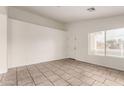 Bright living room featuring tile flooring, neutral walls, and a large window allowing ample natural light at 14915 W Port Royale Ln, Surprise, AZ 85379