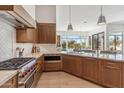 This bright kitchen features stainless steel appliances, wood cabinets, marble countertops, and a view to the backyard at 19910 N 84Th St, Scottsdale, AZ 85255