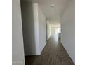 Long hallway with wood-look tile, leading to an open-concept living area, freshly painted white at 46905 W Old Timer Rd, Maricopa, AZ 85139