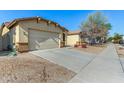 View of the garage and driveway with desert landscaping at 14400 N 136Th Ln, Surprise, AZ 85379