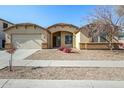 Tan house with a two-car garage and well-manicured front yard at 14400 N 136Th Ln, Surprise, AZ 85379