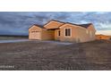 Tan house with a two-car garage and covered patio at 5403 S 360 Th Ave, Tonopah, AZ 85354