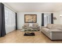 Spacious living room featuring tile floors, gray curtains, and tan sofas at 7461 W Tumblewood Dr, Peoria, AZ 85382