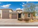 New construction home with stone and stucco exterior, two-car garage, and landscaping at 7718 W Raymond St, Phoenix, AZ 85043