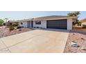 House exterior with a dark garage door and landscaping at 13223 W Gaucho Dr, Sun City West, AZ 85375