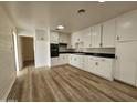 White kitchen cabinets, dark countertop, and laminate floors at 2611 N 40Th Ave, Phoenix, AZ 85009