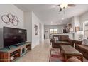 Spacious living room with tile floors, brown sofas, and a large TV at 26236 W Wahalla Ln, Buckeye, AZ 85396